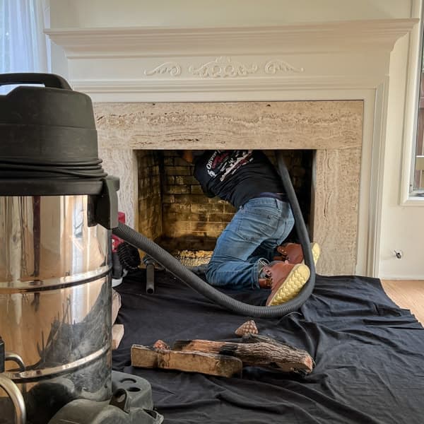 Chimney technician beside a residential roof flue
