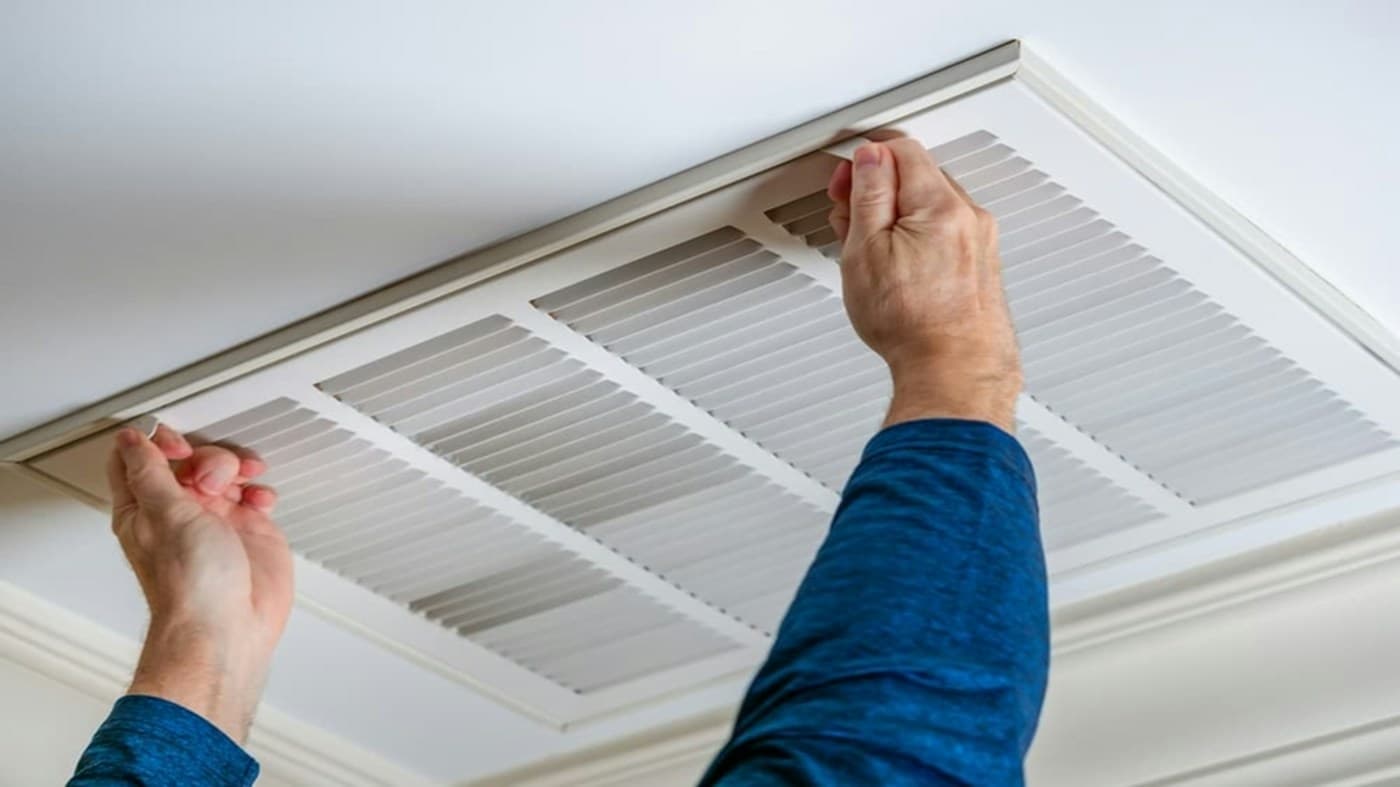Technician opening a ceiling air vent